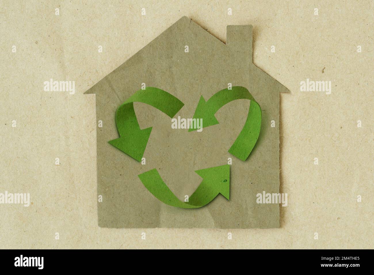 Carta tagliata di casa con il simbolo di riciclaggio a forma di cuore su sfondo di carta riciclata - concetto di casa ed ecologia Foto Stock