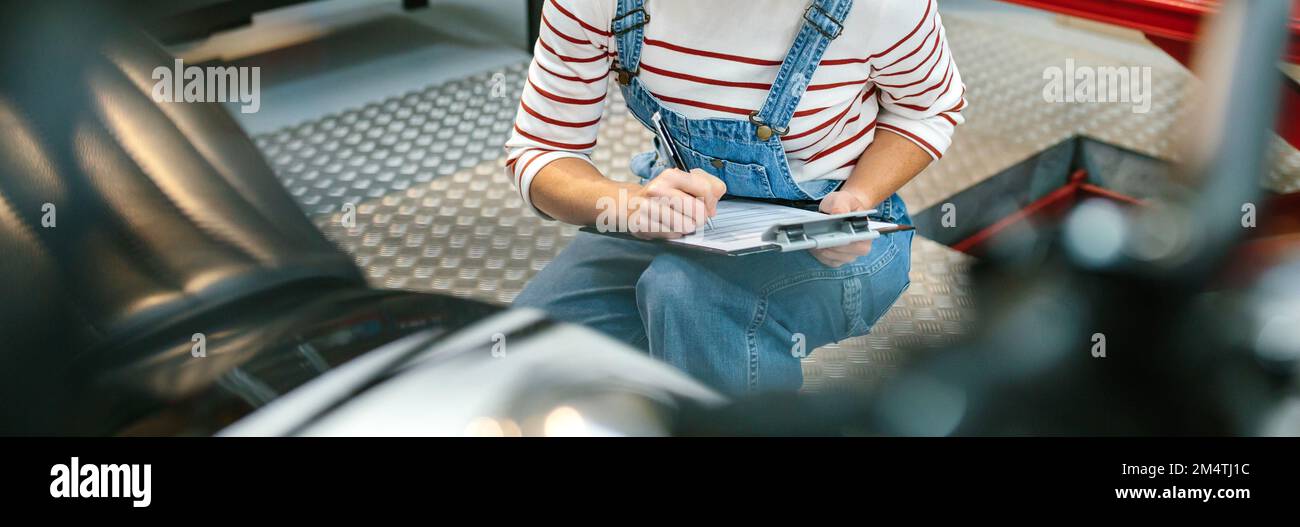 Donna meccanica che controlla la motocicletta in fabbrica Foto Stock