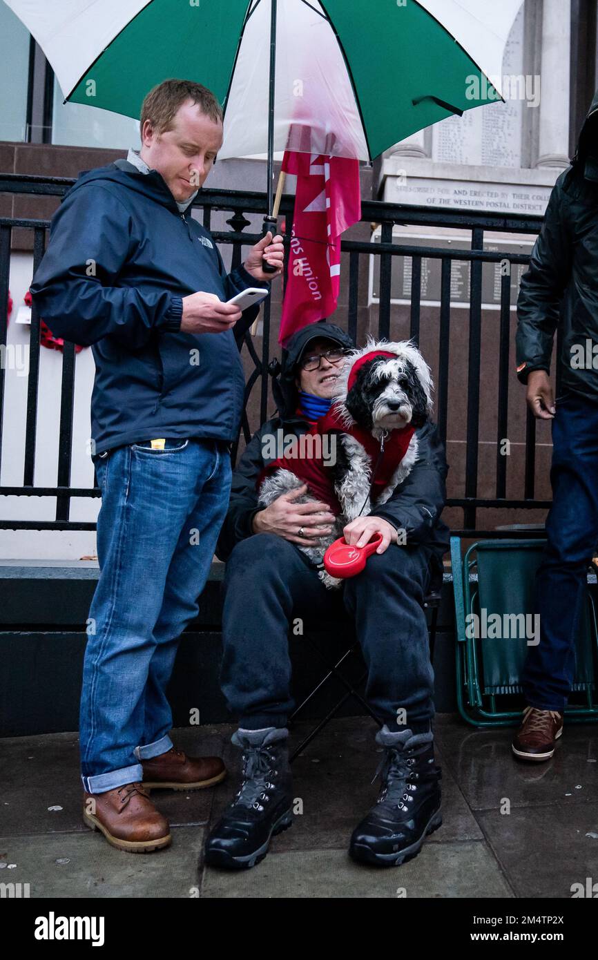 Un membro della Communication Workers Union (CWU) con il suo cane sulla linea del picket fuori dal Mount Pleasant Mail Centre a Farringdon, mentre i Royal Mail lavoratori palcoscenico scioperi freschi nei giorni prima di Natale nella sempre più aspra disputa su posti di lavoro, retribuzioni e condizioni. Data immagine: Venerdì 23 dicembre 2022. Foto Stock