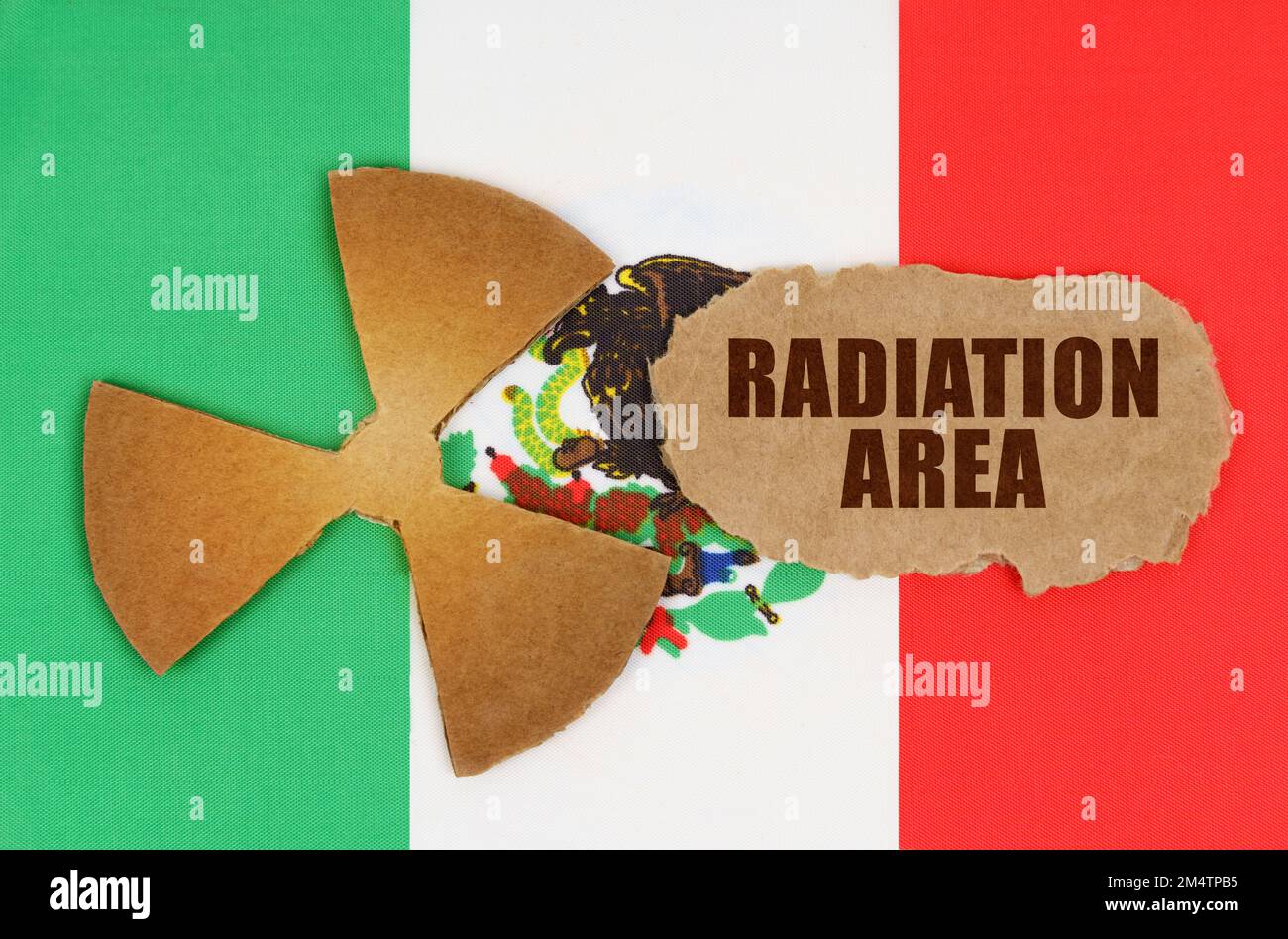 Il concetto di industria e radiazioni. Sulla bandiera del Messico, il simbolo della radioattività e cartone strappato con l'iscrizione - Radiation Area Foto Stock