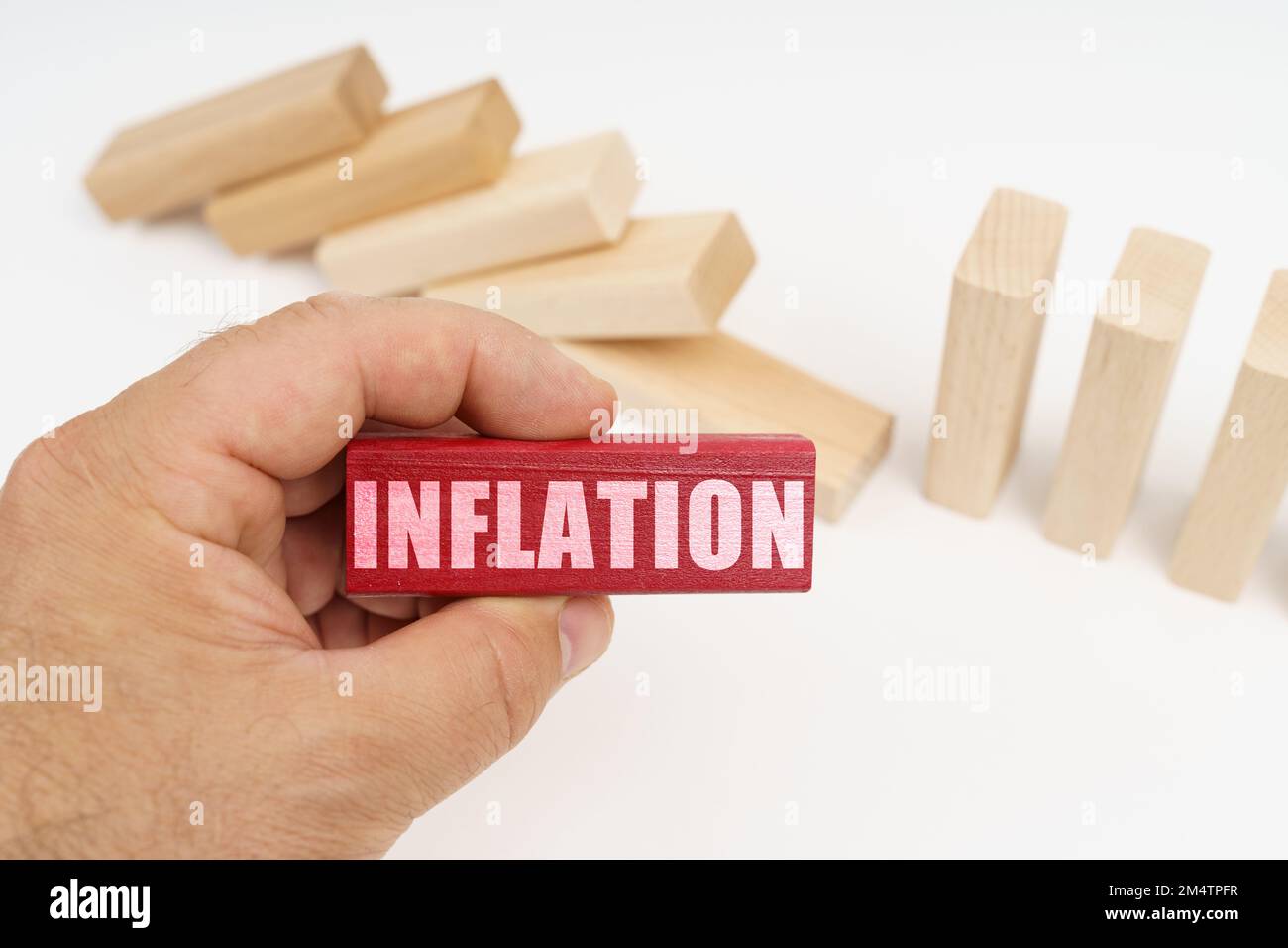 Concetto di business e finanza. In primo piano, una mano con un blocco di legno rosso e l'iscrizione - gonfiaggio, sullo sfondo, caduto blocco di legno Foto Stock