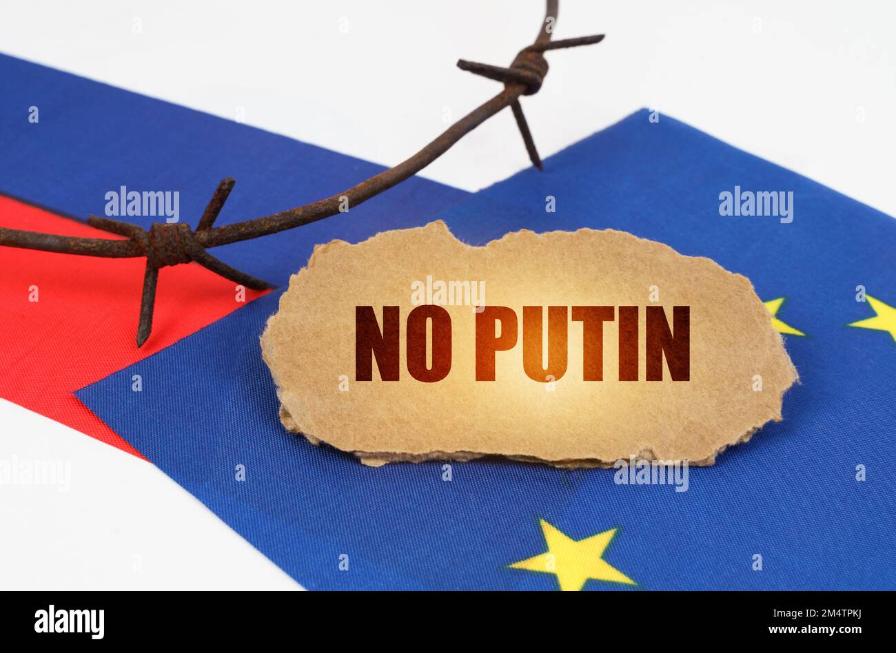 Concetto politico. Sulle bandiere dell'Unione europea e della Russia si trova una targhetta di cartone con l'iscrizione - No Putin. Bandiere separate da spinato wir Foto Stock