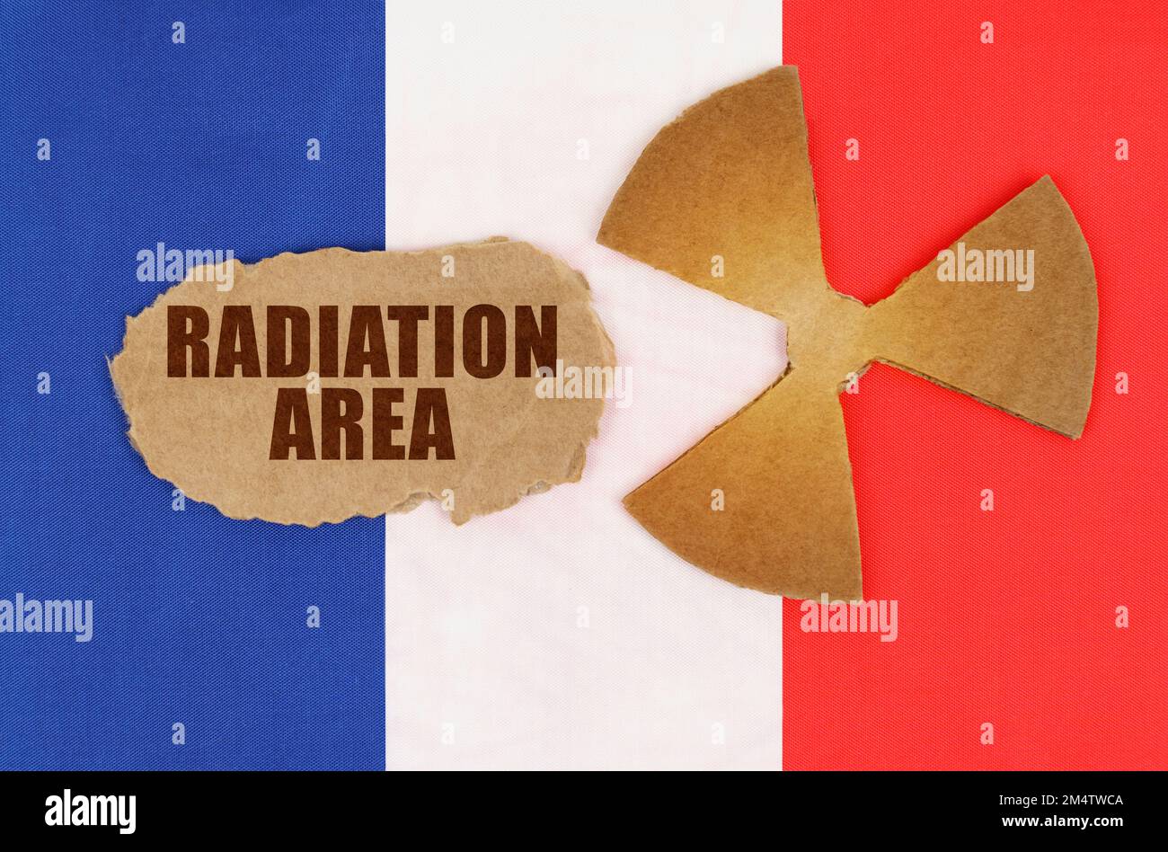 Il concetto di industria e radiazioni. Sulla bandiera della Francia, il simbolo della radioattività e cartone strappato con l'iscrizione - Radiation Area Foto Stock