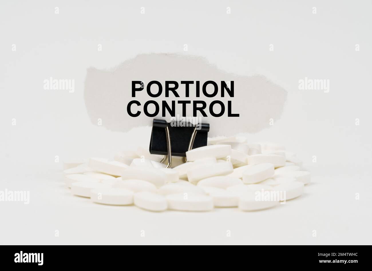 Concetto medico. Su una superficie bianca sono le pillole e la carta strappata con l'iscrizione - controllo della porzione Foto Stock