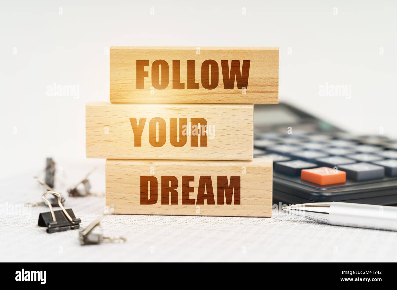 Concetto di business e finanza. Sulle relazioni è una penna, calcolatrice, clip e tavole di legno con l'iscrizione - SEGUIRE IL TUO SOGNO Foto Stock