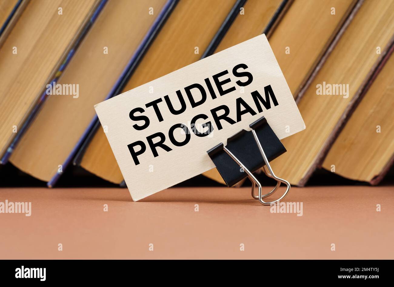 Concetto di educazione e scienza. Sulla tabella sullo sfondo dei libri è presente un biglietto da visita con l'iscrizione - programma di studi Foto Stock