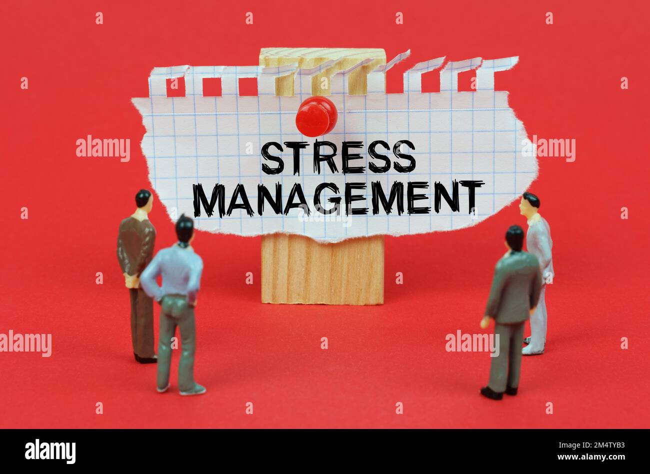 Concetto aziendale. Su uno sfondo rosso sono le figure in miniatura di persone che guardano un annuncio con l'iscrizione - stress Management Foto Stock