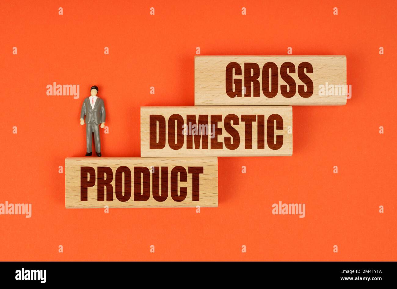 Concetto aziendale. Su una superficie arancione su blocchi di legno con l'iscrizione - PRODOTTO INTERNO LORDO, c'è una figura in miniatura di un uomo d'affari. Foto Stock