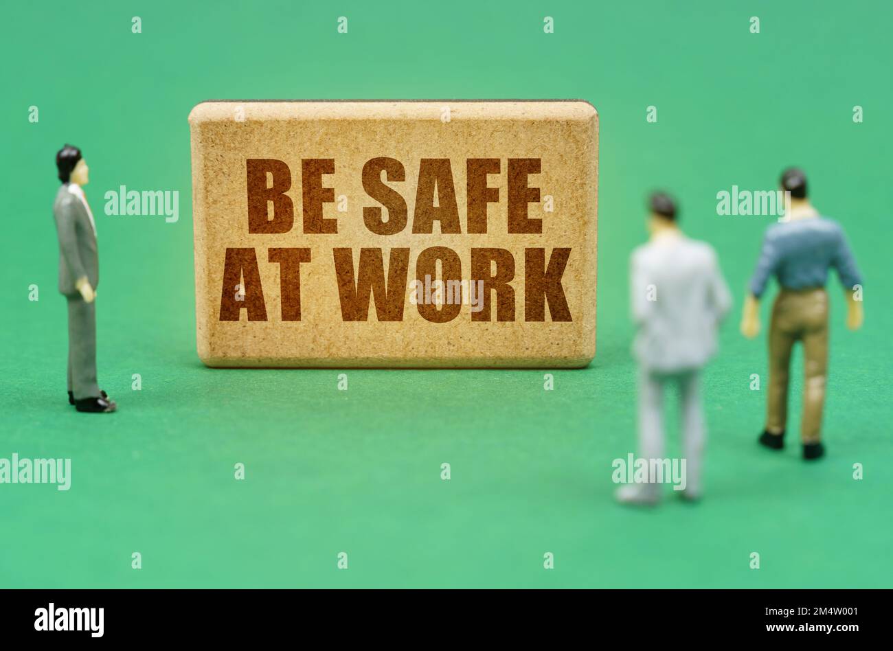 Concetto di sicurezza e assicurazione. Sulla superficie verde ci sono figure di persone e un segno con l'iscrizione - essere al sicuro sul lavoro Foto Stock