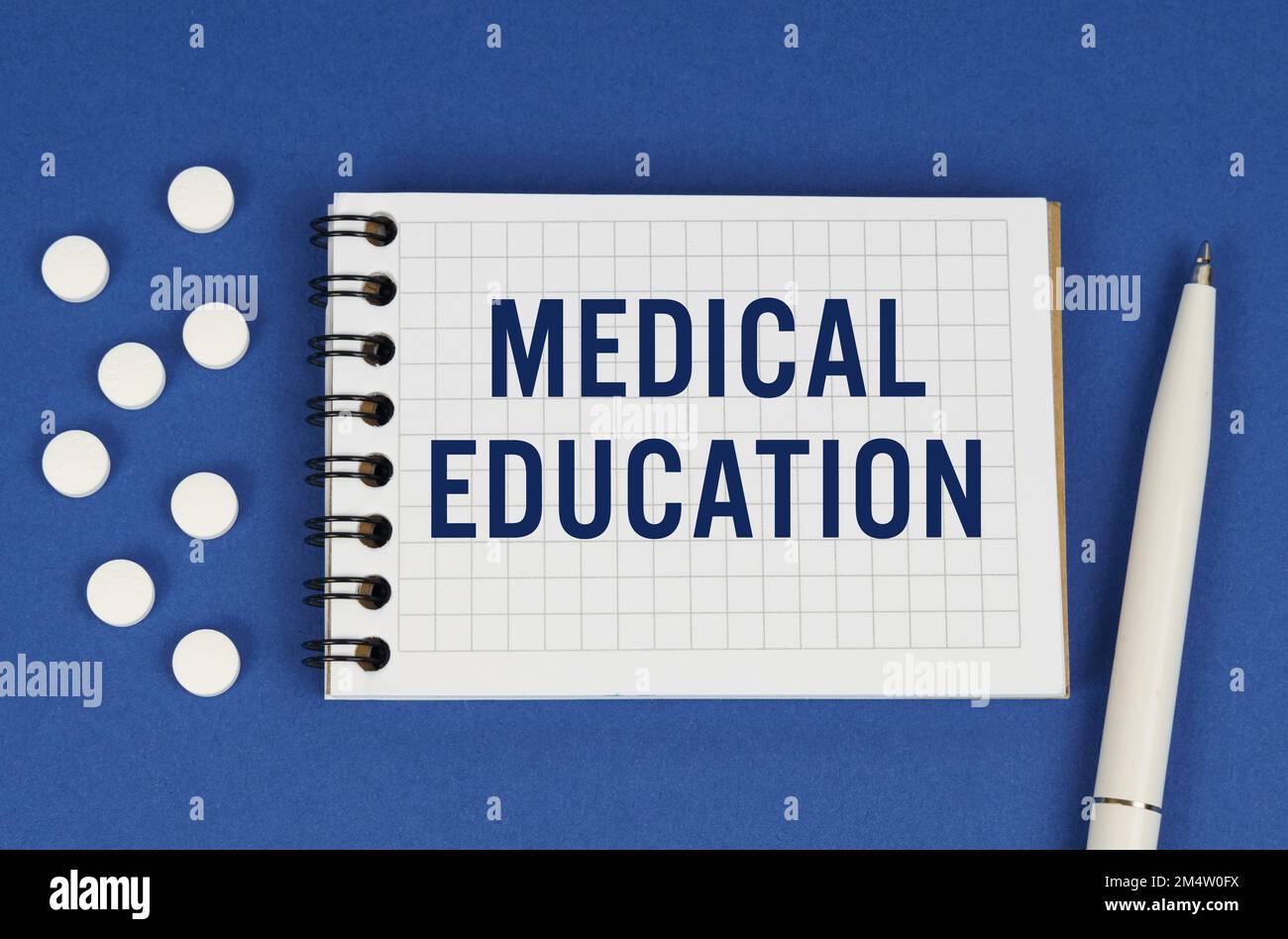 Concetto medico. Su sfondo blu, una penna, tavolette e un blocco note con l'iscrizione - EDUCAZIONE MEDICA Foto Stock