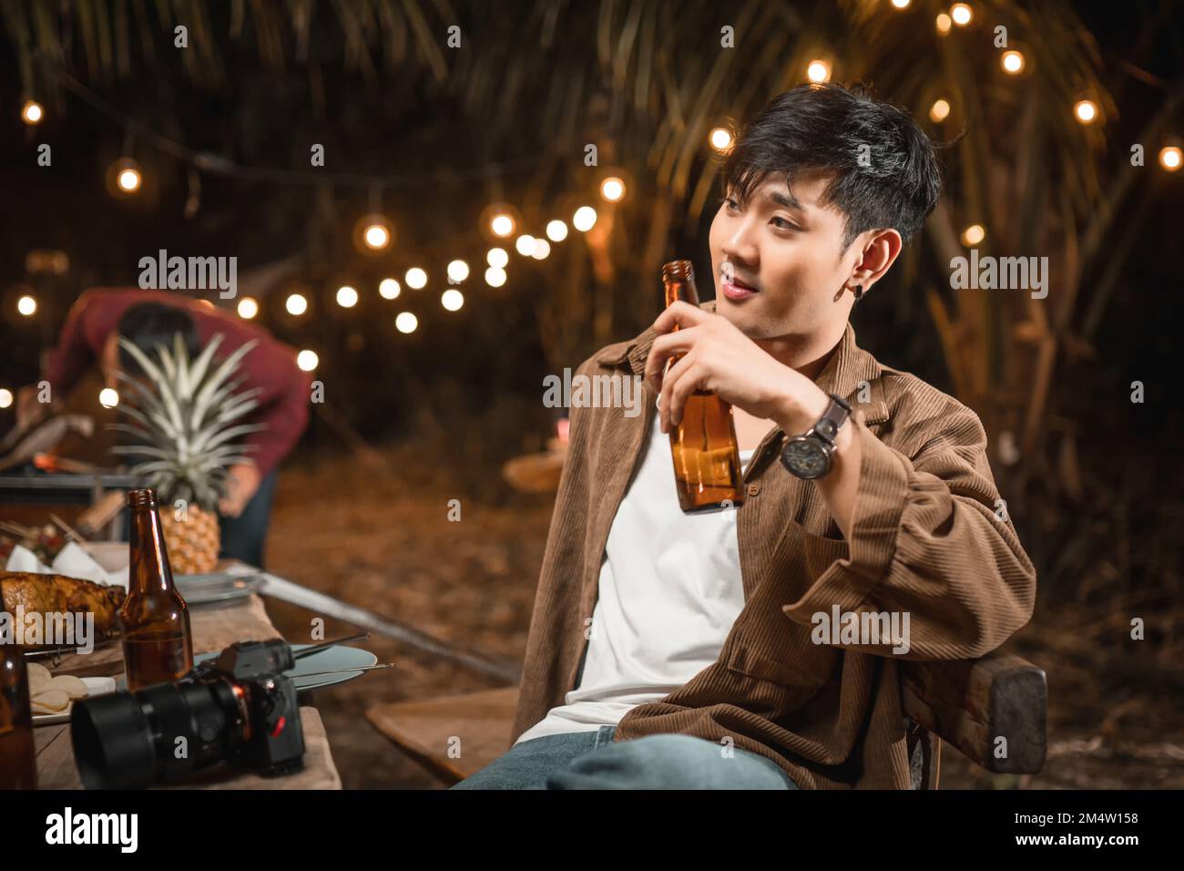 I giovani maschi asiatici in possesso di una bottiglia di birra godono la festa notturna Foto Stock