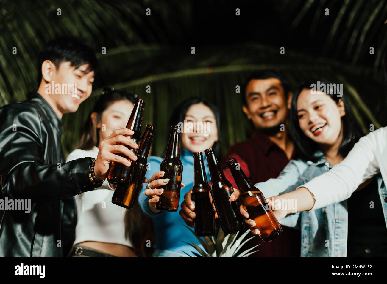 Amici asiatici bere birra all'aperto in giardino Foto Stock