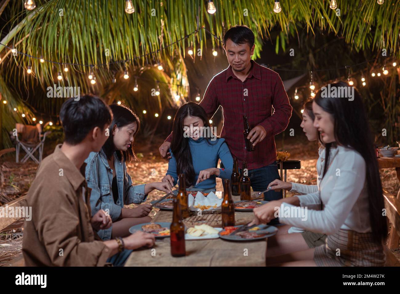 Giovane coppia che cena con gli amici al backyard party Foto Stock