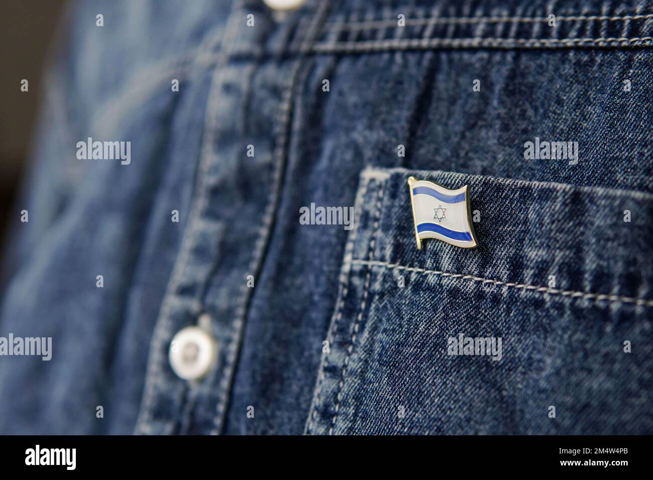 Il distintivo di metallo con la bandiera di Israele è fissato su una giacca di jeans blu. Concetto di patriottismo israeliano. Festa di Independence Day in Israele. Foto Stock