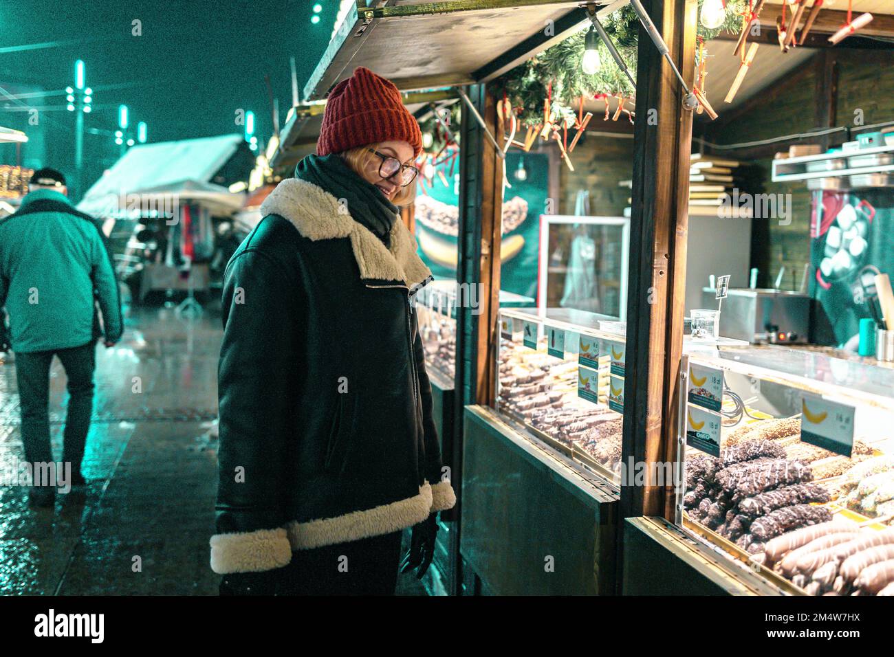 Mela immersa nel cioccolato per natale. Felice donna bionda carina nel negozio di Natale al Town Hall Square a Katowice, Polonia. Shopping Foto Stock