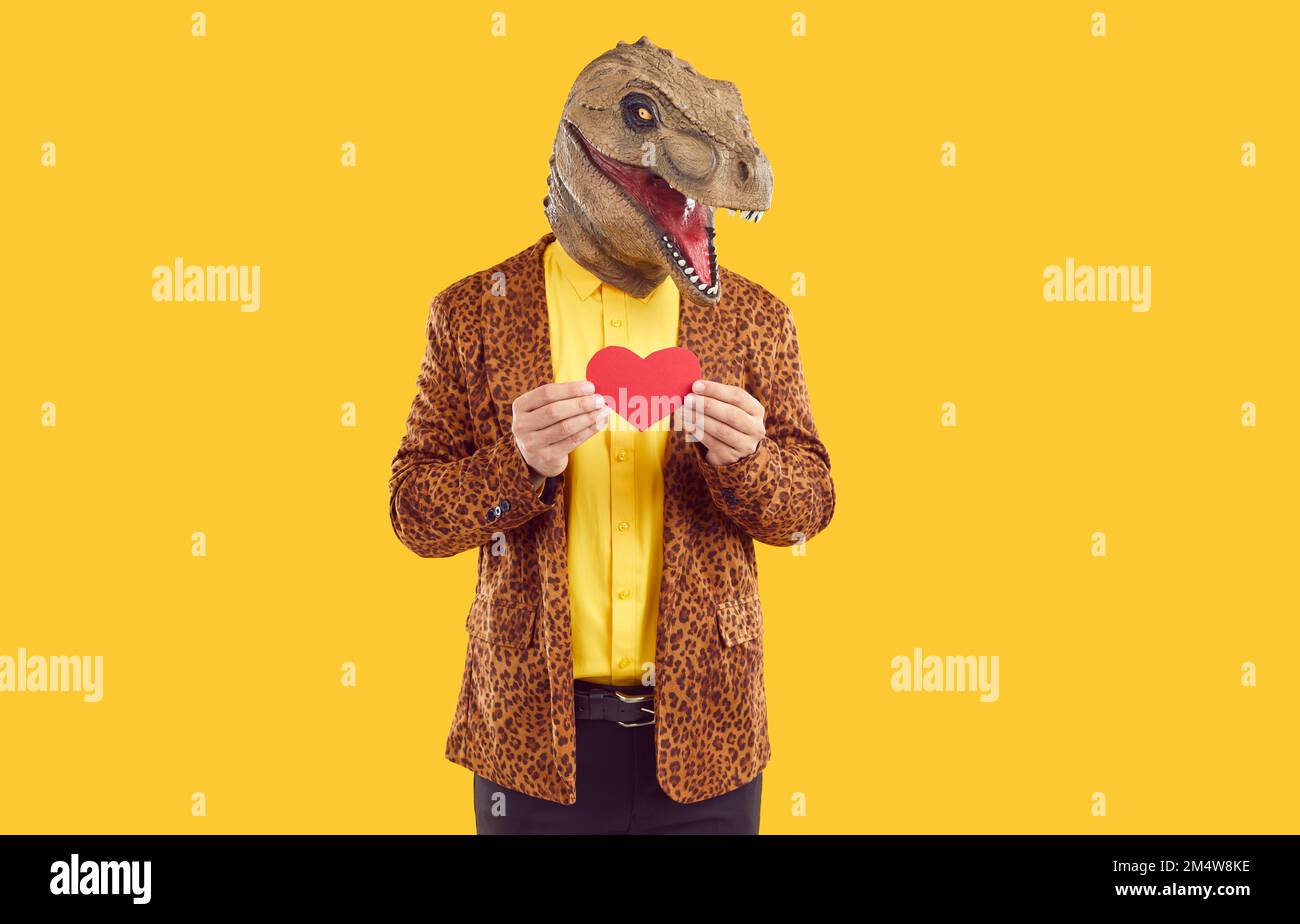 Dinosauro uomo che tiene il cuore rosso su sfondo isolato studio Foto Stock