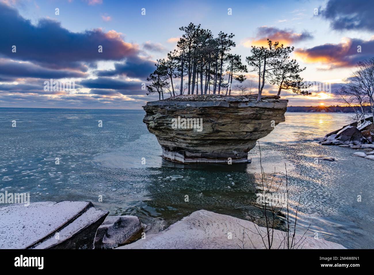 L'alba a Turnip Rock, sulla punta del pollice del Michigan vicino a Port Austin, è mostrata all'inizio dell'inverno. Il ghiaccio del pancake galleggia sulla superficie del lago Huron Foto Stock