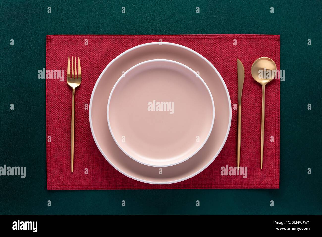 Piastra vuota con forchetta e coltello su tavolo verde scuro. Ambiente festivo con tovagliolo rosso e posate d'oro. Vista dall'alto. Tavolo da pranzo nel ristorante. Auto Foto Stock