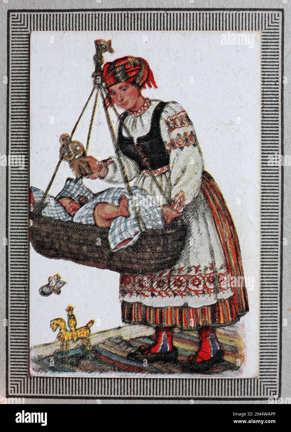 Trachten in Deutschland im 19. Jahrhundert, Ostpreussen, Frau, ostpreußische Bäuerin mit Baby in der Wiege, Historisch, restaurierte digitale Reproduktion von einem Sammelbild aus dem Jahre ca 1910 / costumi tradizionali in Germania nel 19th ° secolo, Prussia orientale, donna, contadina prussiana orientale con bambino in culla, storica, riproduzione restaurata digitalmente da un quadro collettivo dell'anno 1910 circa Foto Stock