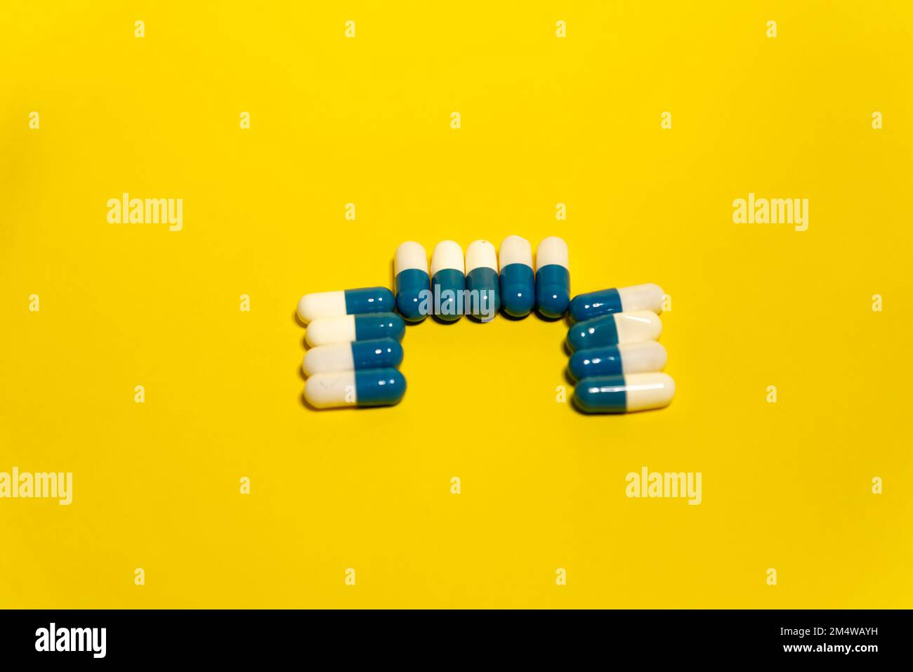 Le pillole blu e bianche isolate su sfondo giallo Foto Stock