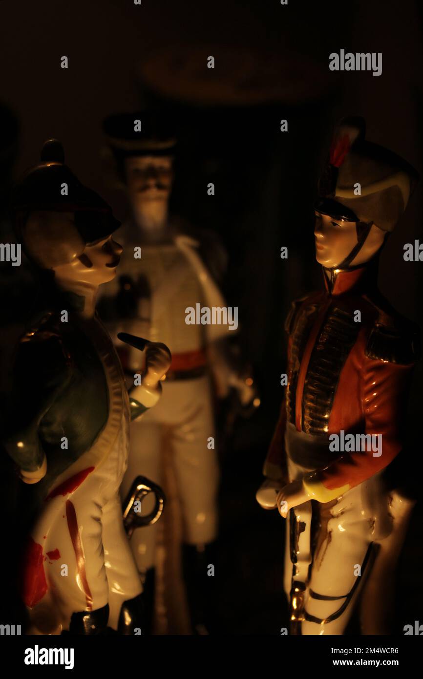 Tre statuine di porcellana soldato napoleonico in piedi come se fossero accese da un falò Foto Stock