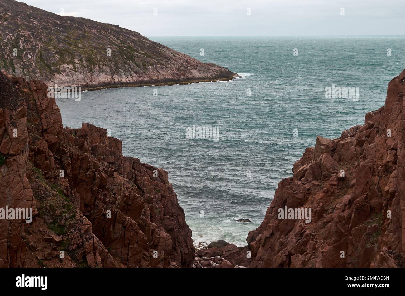 Scogliera rocciosa rossa sopra il mare turchese calmo Foto Stock