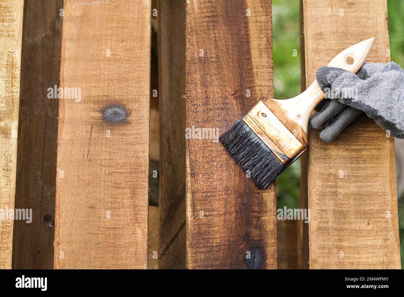 Pallet in legno colorato. Outdoor superficie di legno Sealant Paintbrush applicazione primo piano Foto Stock