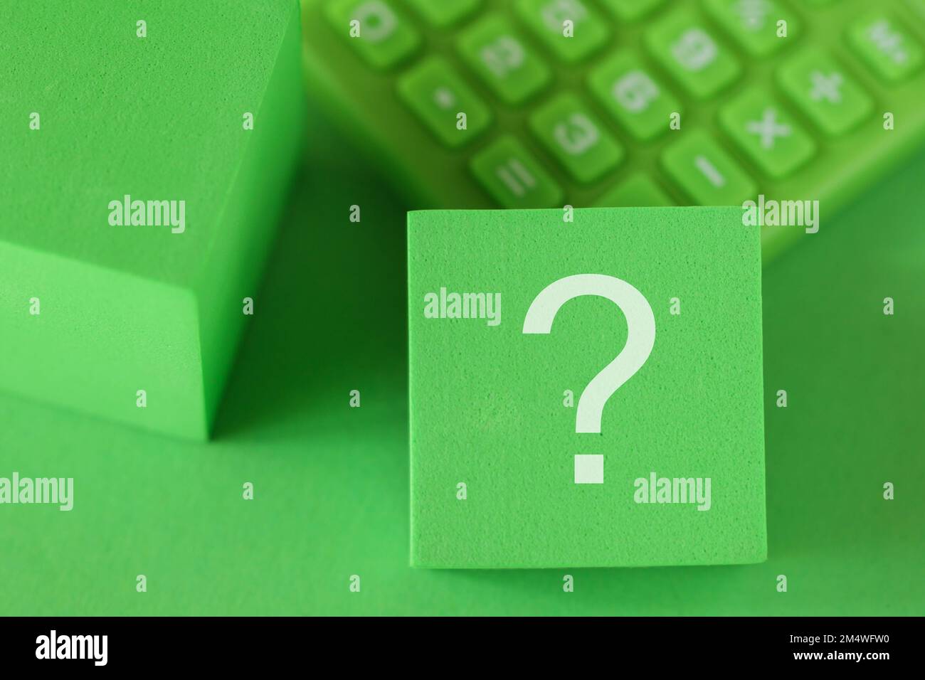Segno del punto interrogativo sul cubo a blocchi, calcolatrice verde, sfondo verde. Concetto di supporto ESG Foto Stock