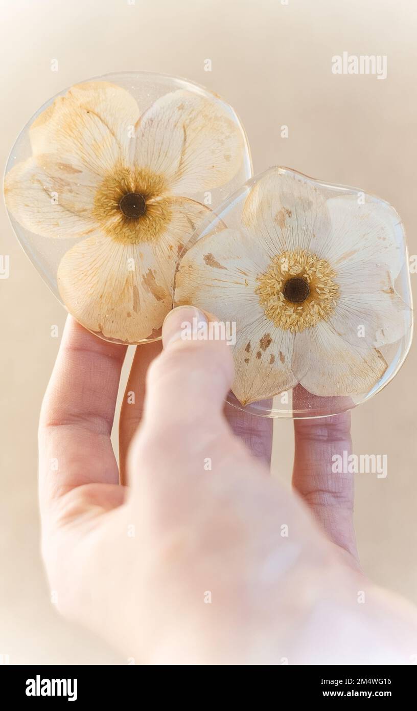 Primo piano mano femminile che mostra fiori secchi in resina