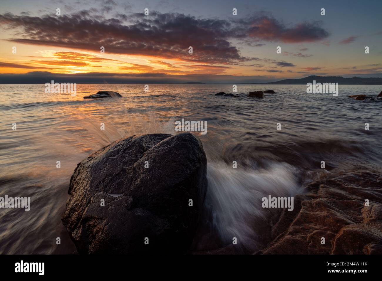 Mattinata tranquilla sul lago Superior mentre il sole sorge e rompe l'orizzonte per illuminare un nuovo giorno vicino a Marquette Michigan, nella penisola superiore. STATI UNITI Foto Stock