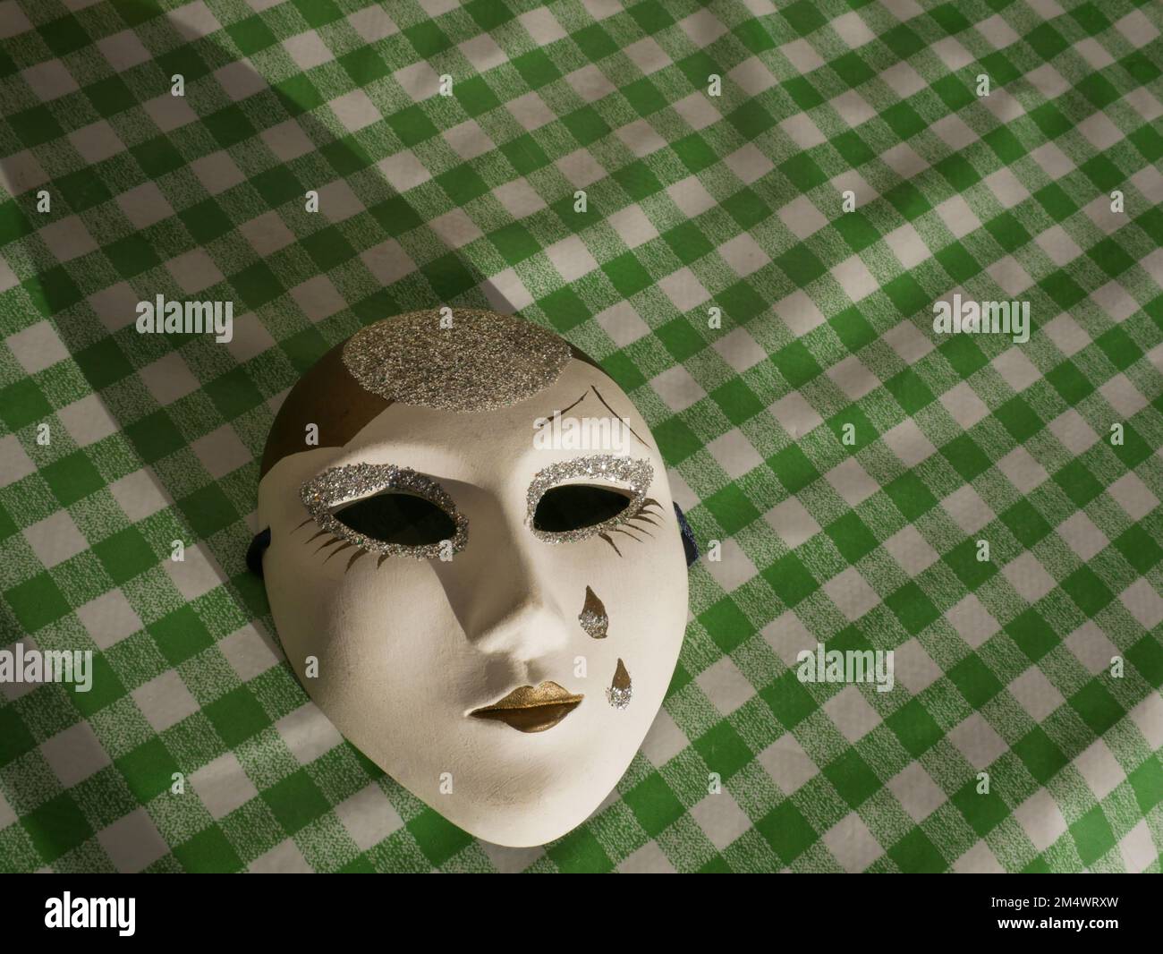 Piccola maschera veneziana dipinta a mano su fondo a quadri verde e bianco - Venezia - Italia Foto Stock