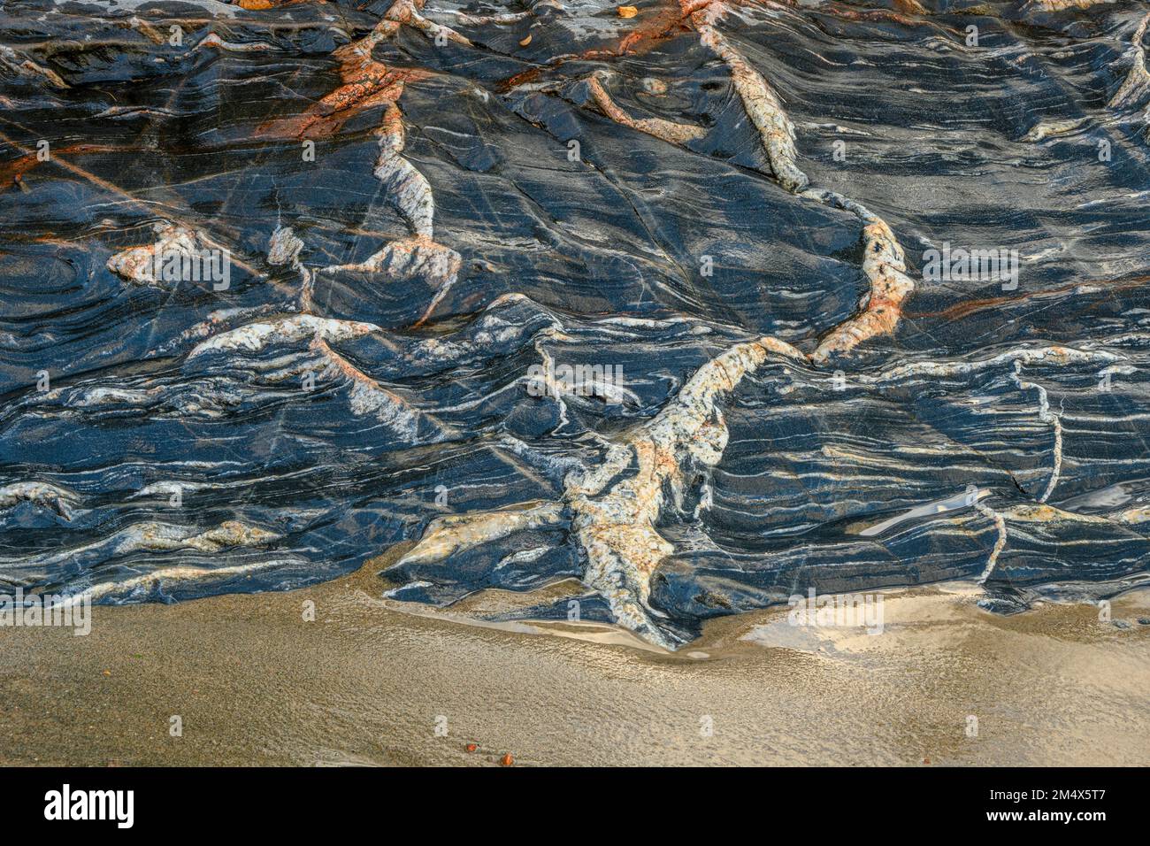 Onde entranti, sabbia bagnata e un affioramento roccioso con intrusioni ignee, Lake Superior Provincial Park- Coldwater River Bay, Ontario, Canada Foto Stock