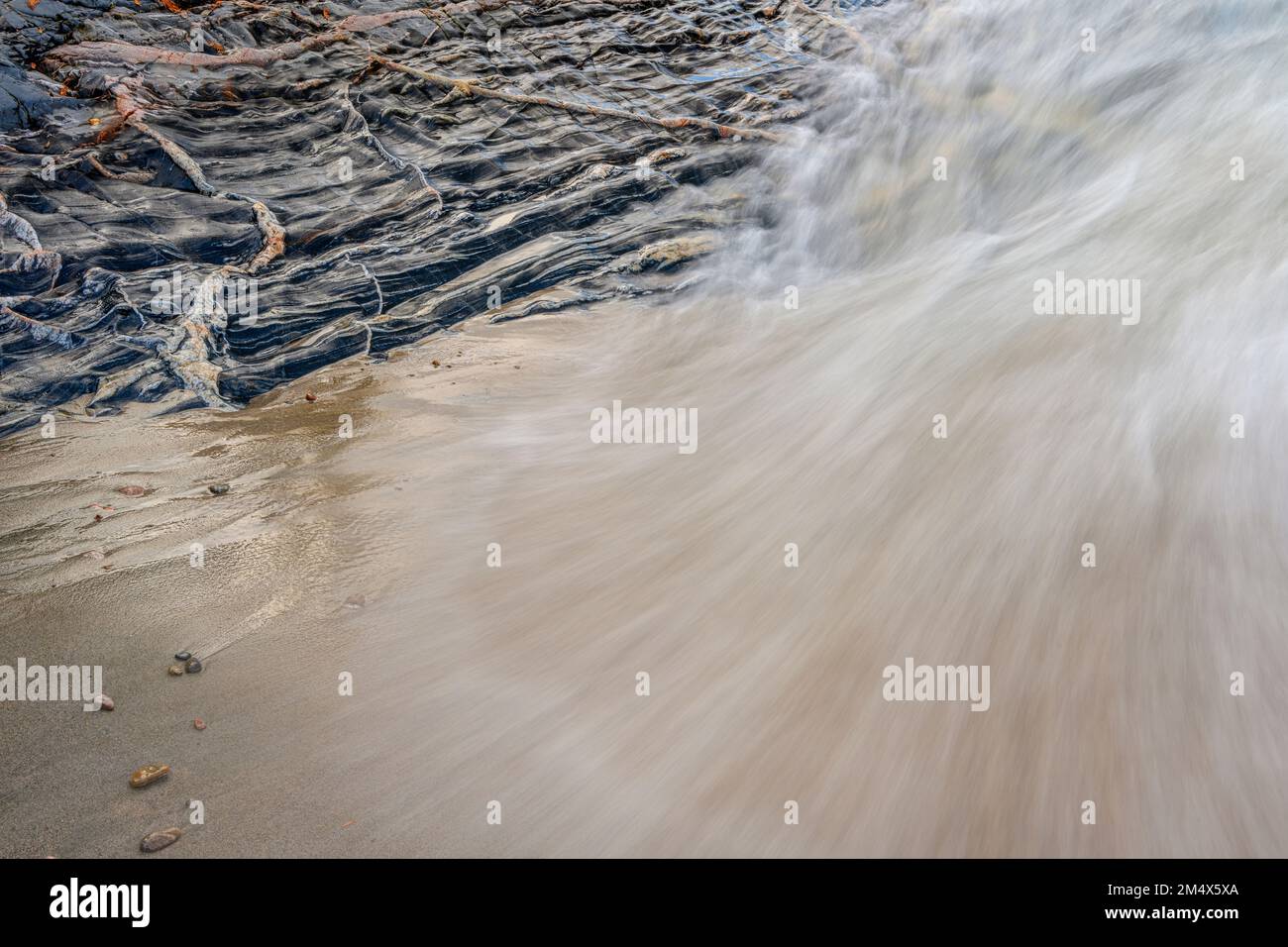 Onde entranti, sabbia bagnata e un affioramento roccioso con intrusioni ignee, Lake Superior Provincial Park- Coldwater River Bay, Ontario, Canada Foto Stock