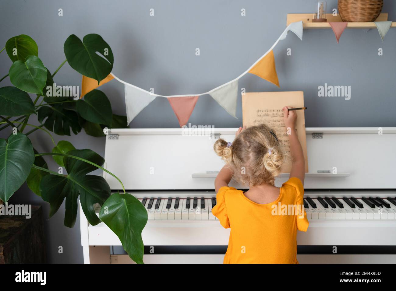 Ragazza che scrive nota musicale sul foglio a casa Foto Stock
