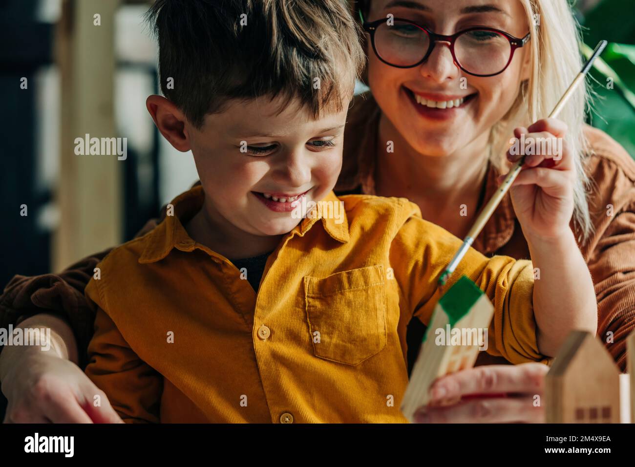 Felice madre e figlio pittura case modello in legno Foto Stock