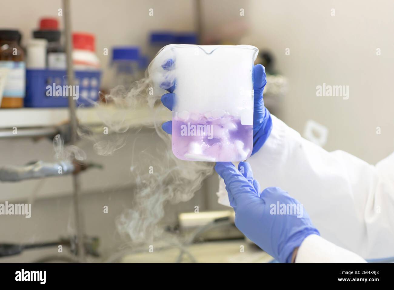 Mani dello scienziato che sperimenta con azoto liquido in laboratorio Foto Stock