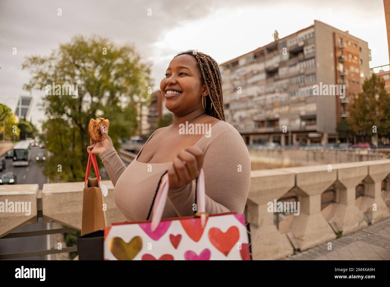 Donna sorridente che cammina con le borse per lo shopping sul sentiero Foto Stock