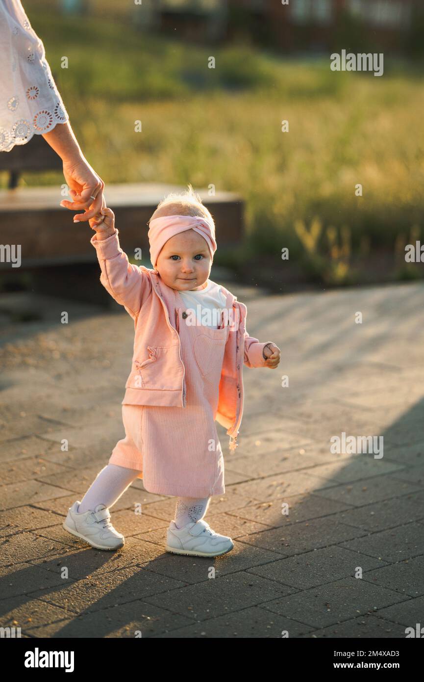 Ragazza cute del bambino che tiene la mano della madre e che cammina sul sentiero Foto Stock