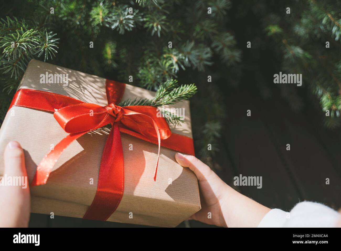 Mano della ragazza che tiene la scatola del regalo di Natale legata con il nastro rosso Foto Stock