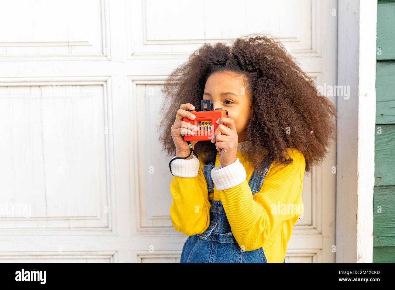 Ragazza che gioca con la macchina fotografica giocattolo vicino alla porta Foto Stock