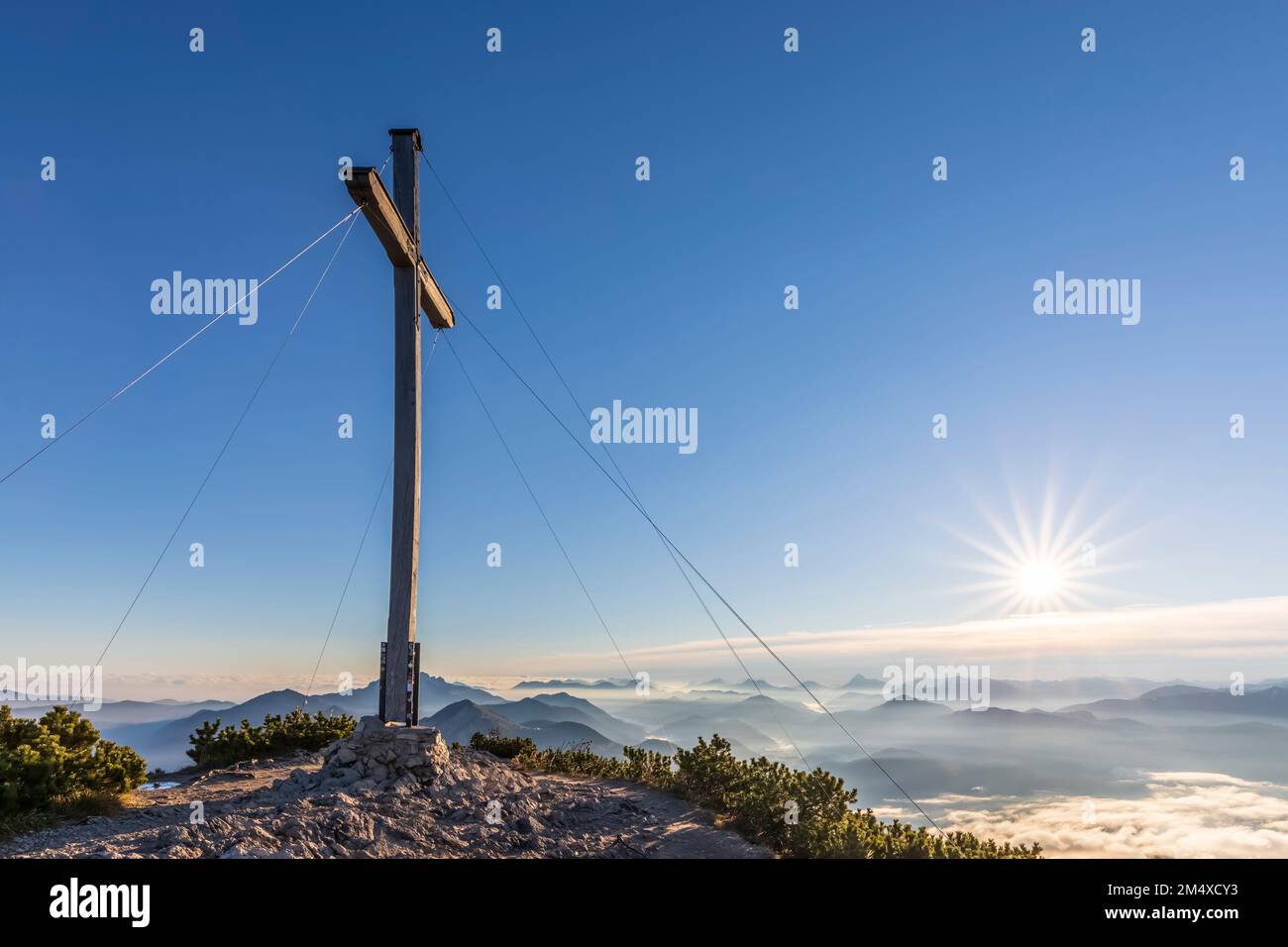 Germania, Baviera, cima croce di Herzogstand montagna con il sole che sorge sullo sfondo Foto Stock