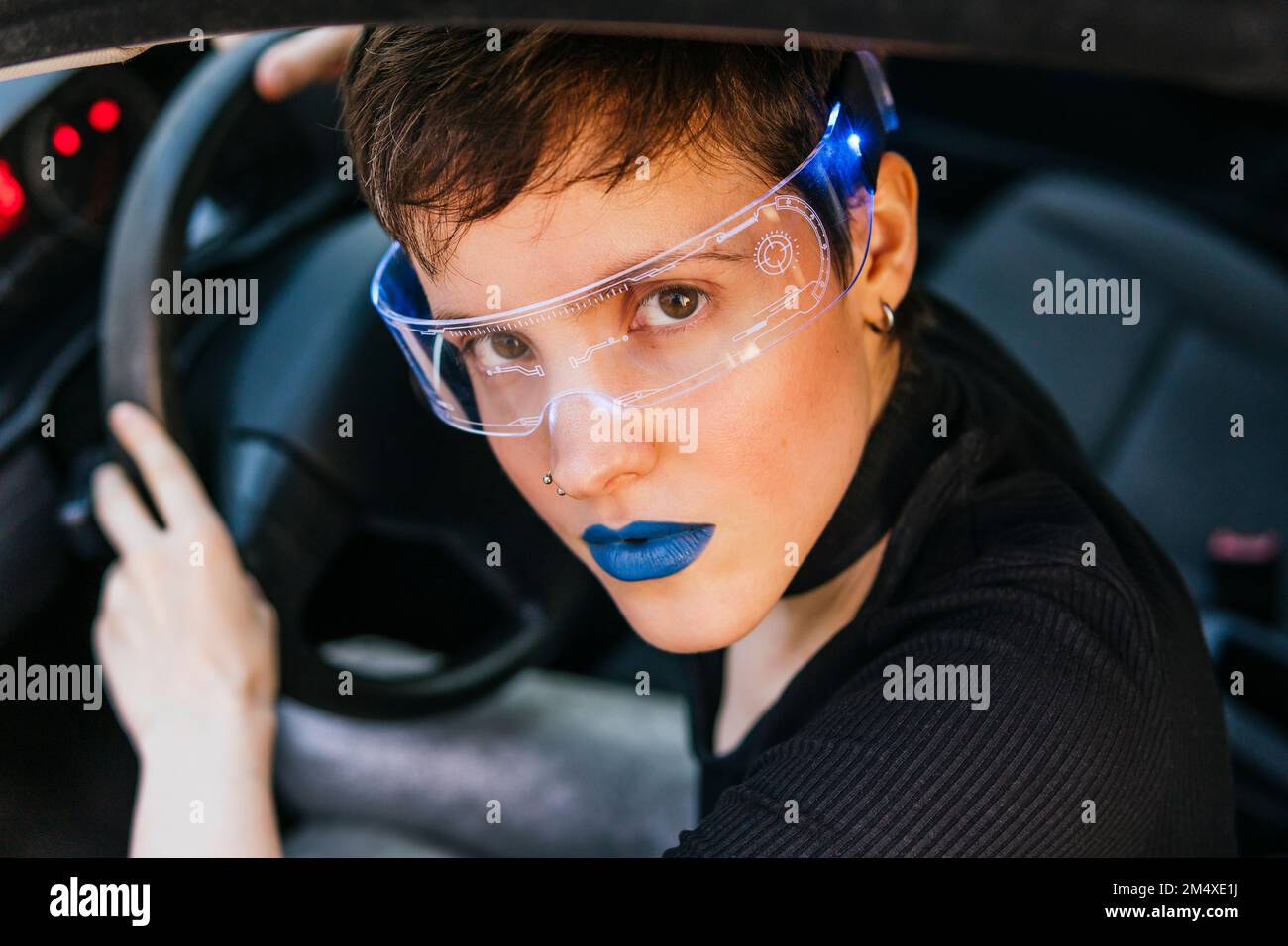 Donna con rossetto blu che indossa occhiali intelligenti in auto Foto Stock