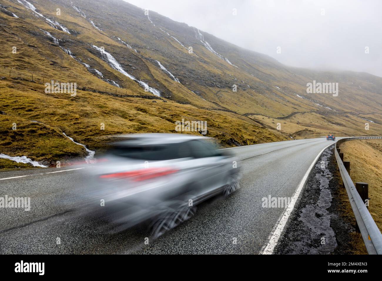 Auto sfocata sulla strada di fronte alla montagna Foto Stock