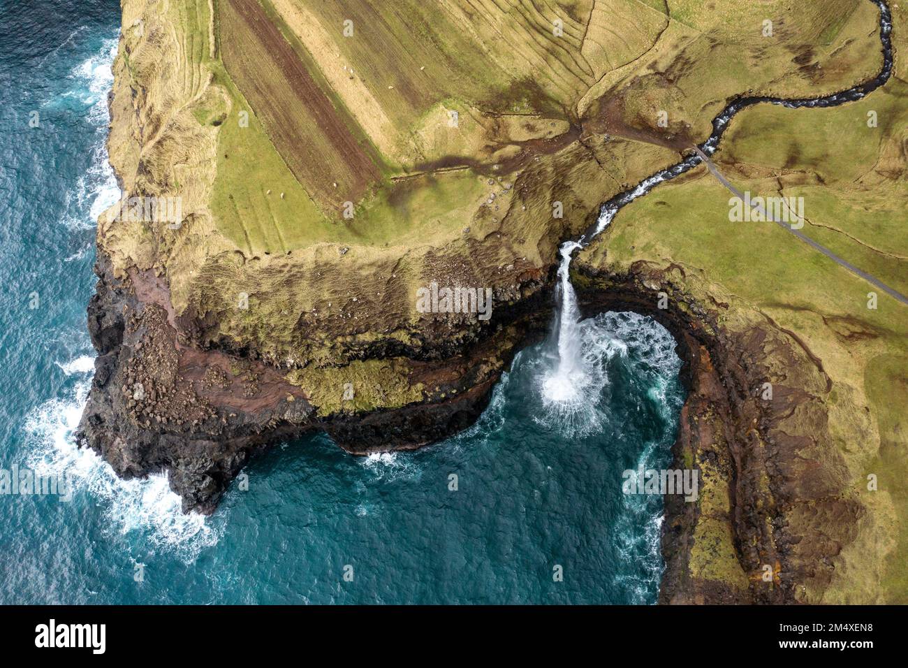 Cascata di Mulafossur tra montagne rocciose dal mare Foto Stock