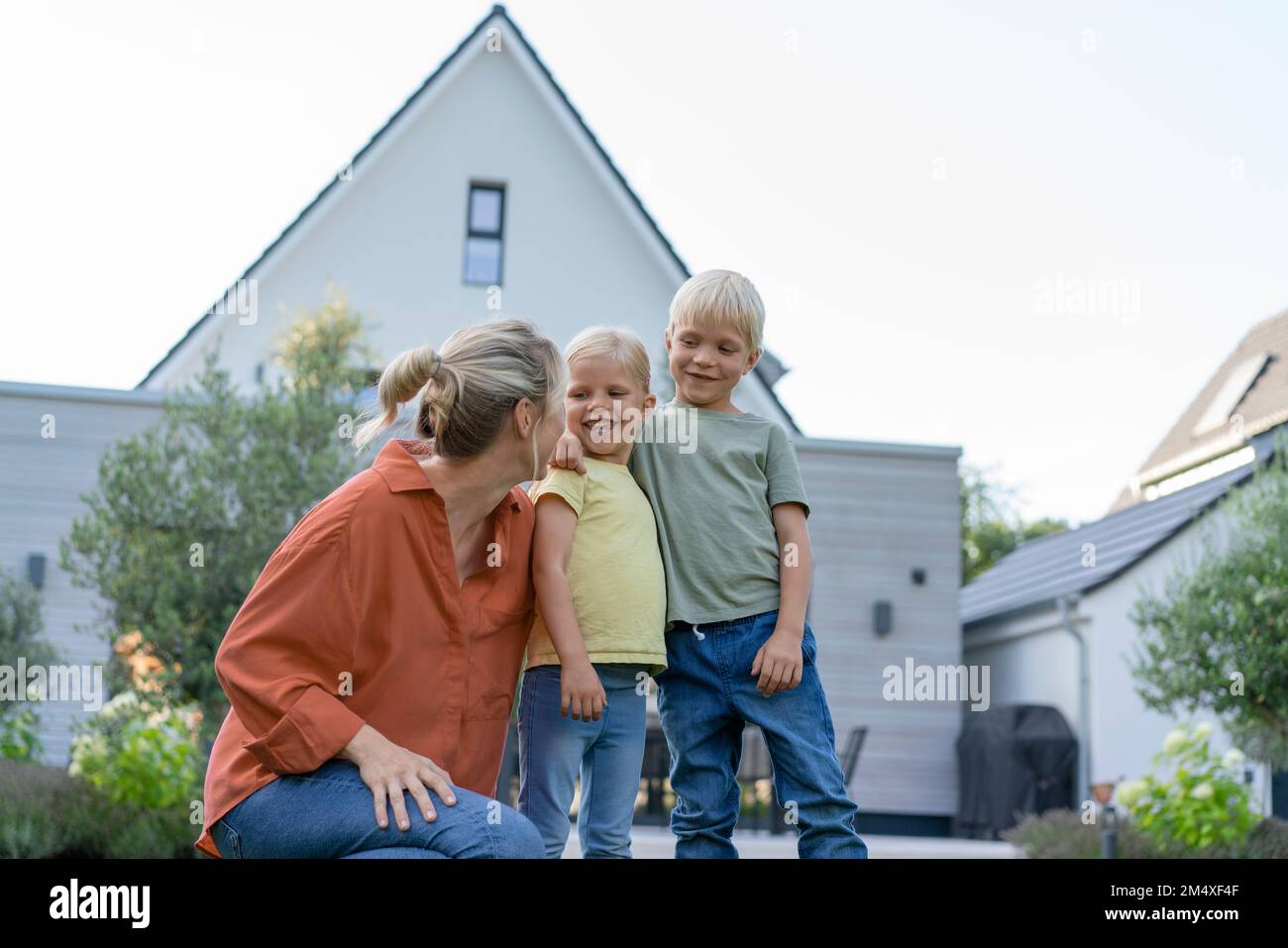 Figli felici che guardano la madre di fronte a casa Foto Stock