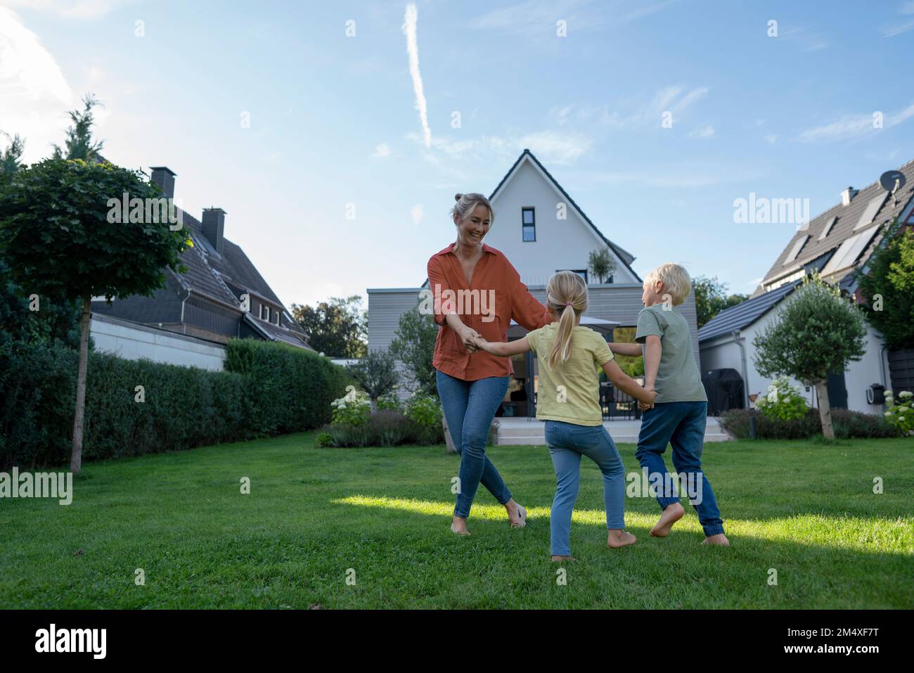 Giocoso anello di gioco della madre intorno Rosy con i bambini in giardino Foto Stock