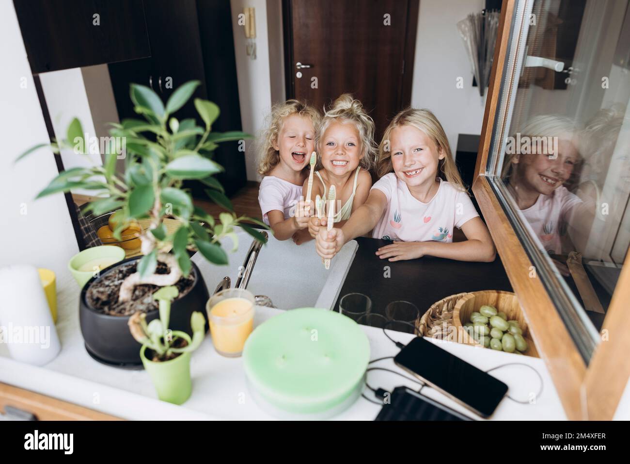 Ragazze felici che mostrano gli spazzolini di legno in cucina Foto Stock