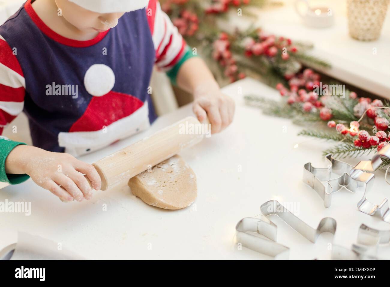 Ragazzo che arrotola l'impasto di pan di zenzero al banco della cucina Foto Stock