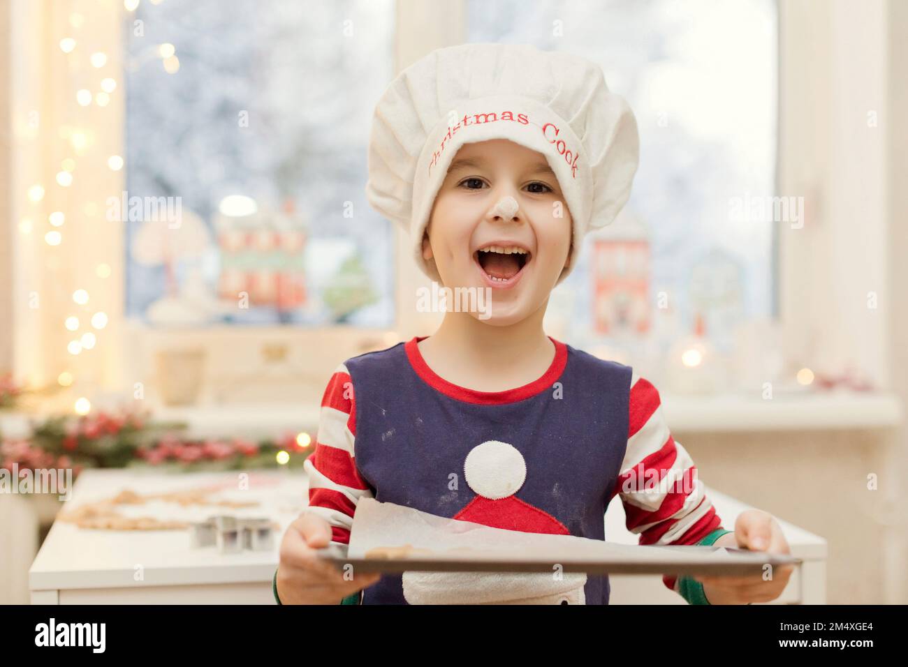 Felice ragazzo carino che tiene la placca da forno in cucina Foto Stock
