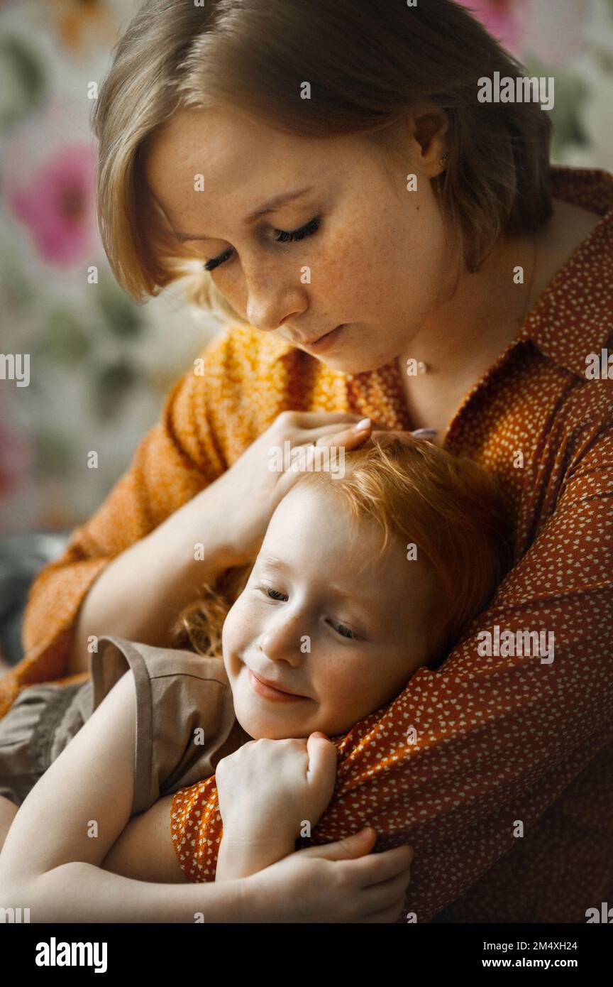 Giovane madre che abbraccia la figlia a casa Foto Stock